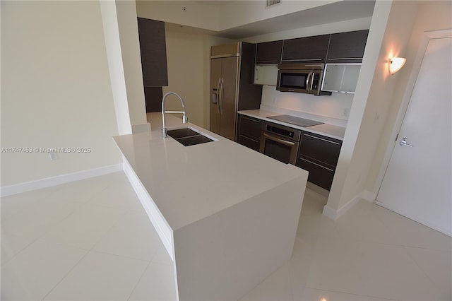 kitchen featuring appliances with stainless steel finishes, sink, light tile patterned floors, kitchen peninsula, and dark brown cabinets