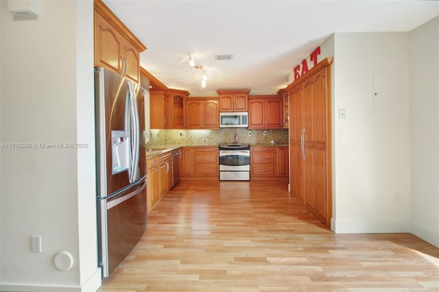 kitchen featuring appliances with stainless steel finishes, light wood-type flooring, visible vents, and tasteful backsplash