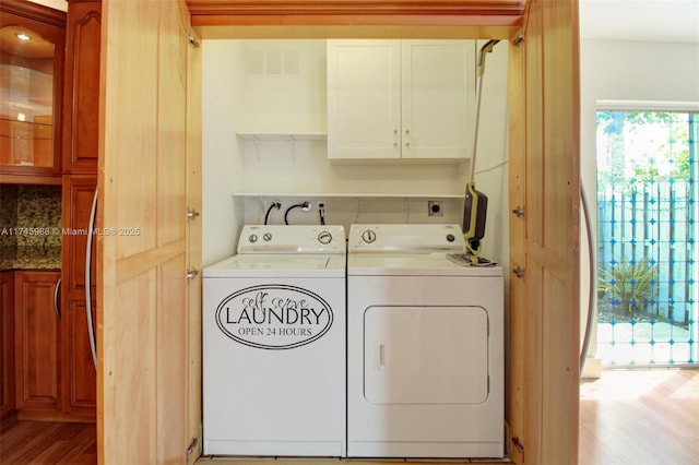 laundry room with light wood-type flooring, washer and dryer, and cabinet space