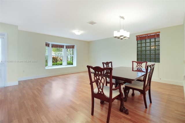 dining room with light wood-style floors, visible vents, baseboards, and an inviting chandelier