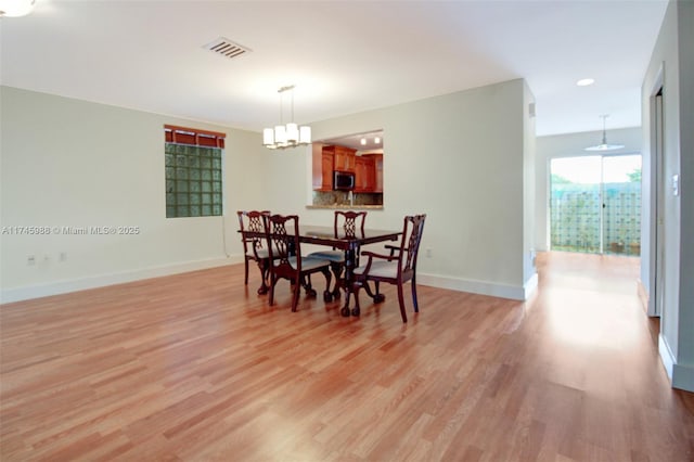 dining space featuring light wood finished floors, visible vents, baseboards, and an inviting chandelier