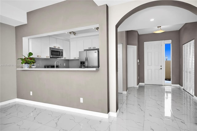 kitchen featuring white cabinets, stainless steel appliances, and decorative backsplash