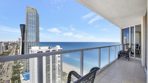 balcony with a water view and a view of the beach