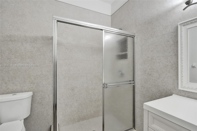 bathroom featuring tile walls, a shower with door, and toilet