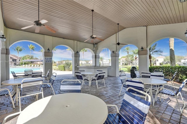 view of patio / terrace featuring an outdoor bar, ceiling fan, and a community pool