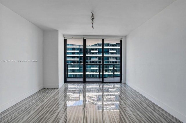 empty room featuring track lighting and floor to ceiling windows