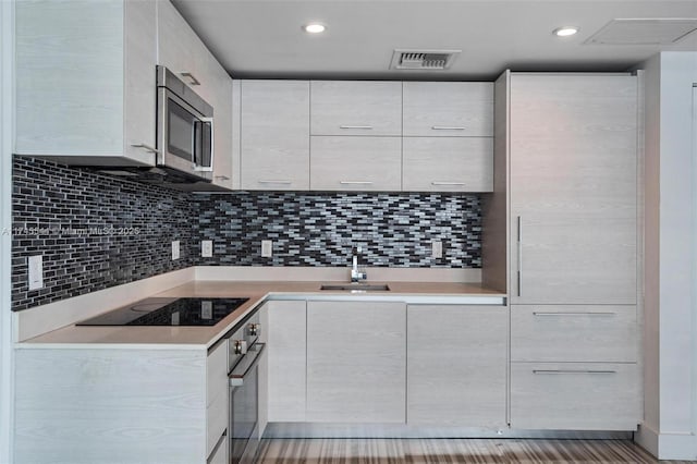 kitchen featuring sink, white cabinetry, stainless steel appliances, and decorative backsplash