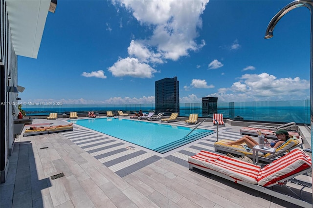 view of swimming pool featuring a patio and a water view