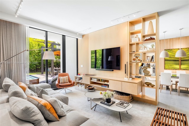 tiled living room with built in features, a wall of windows, and rail lighting