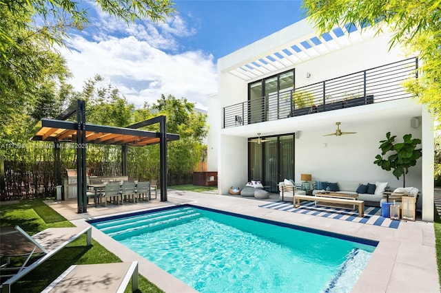 rear view of property featuring exterior kitchen, ceiling fan, a patio area, a balcony, and an outdoor hangout area