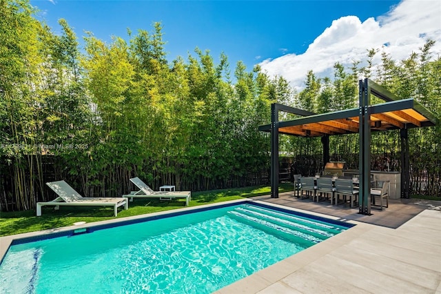 view of pool with an outdoor kitchen, a lawn, and a patio area