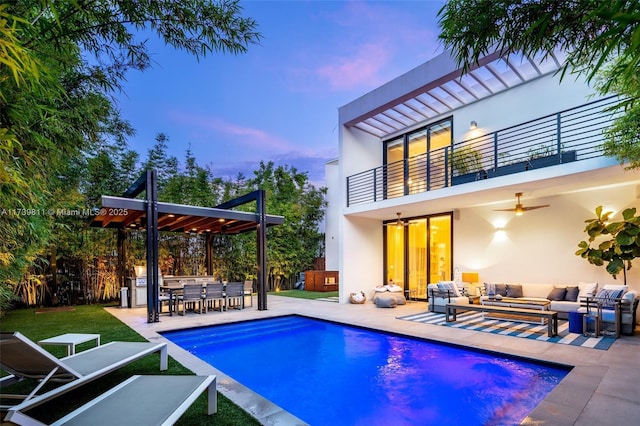 back house at dusk featuring an outdoor living space, a balcony, ceiling fan, and a patio area