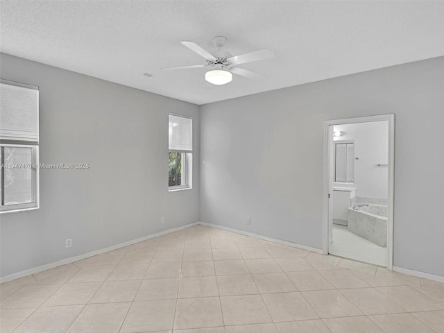 empty room featuring a textured ceiling, ceiling fan, and light tile patterned floors