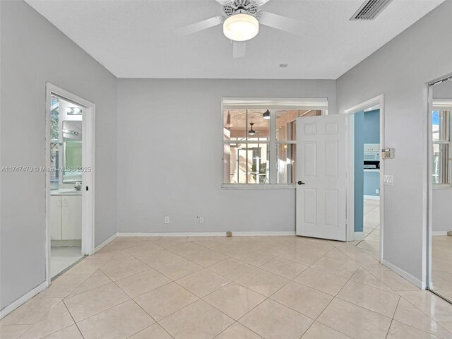 tiled spare room with ceiling fan