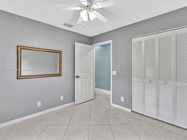 unfurnished bedroom featuring light tile patterned floors, ceiling fan, a closet, and a textured ceiling