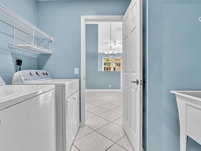 laundry room featuring light tile patterned flooring, washer and dryer, and an inviting chandelier