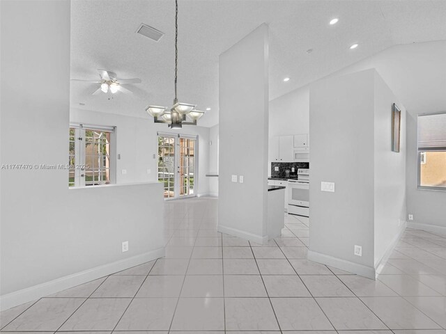 kitchen with white cabinetry, a wealth of natural light, white appliances, vaulted ceiling, and light tile patterned floors