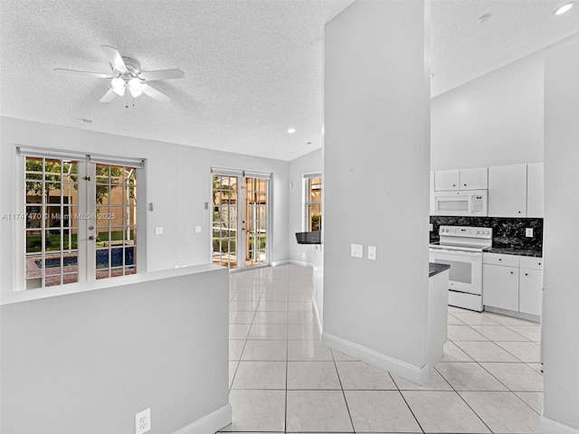 interior space with light tile patterned floors, a textured ceiling, and a healthy amount of sunlight