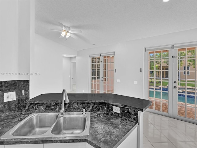 kitchen with a textured ceiling, french doors, light tile patterned floors, sink, and kitchen peninsula