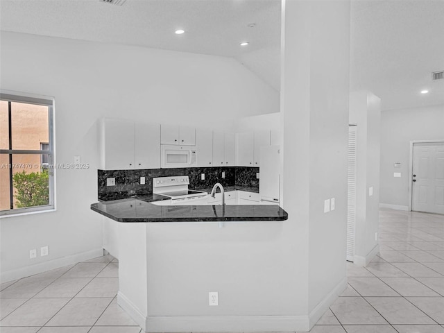 kitchen with kitchen peninsula, backsplash, white appliances, light tile patterned floors, and white cabinets