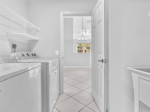 clothes washing area with separate washer and dryer, a chandelier, and light tile patterned floors