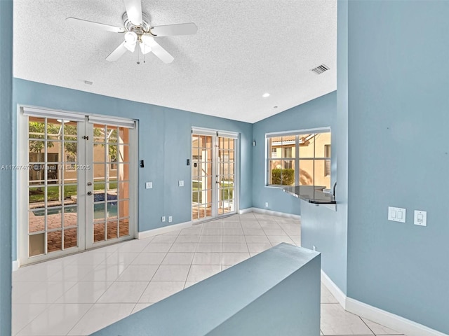 tiled spare room with a textured ceiling, french doors, vaulted ceiling, and ceiling fan