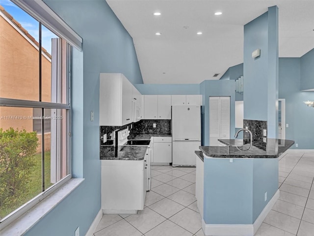 kitchen featuring dark stone counters, white appliances, white cabinets, and a wealth of natural light