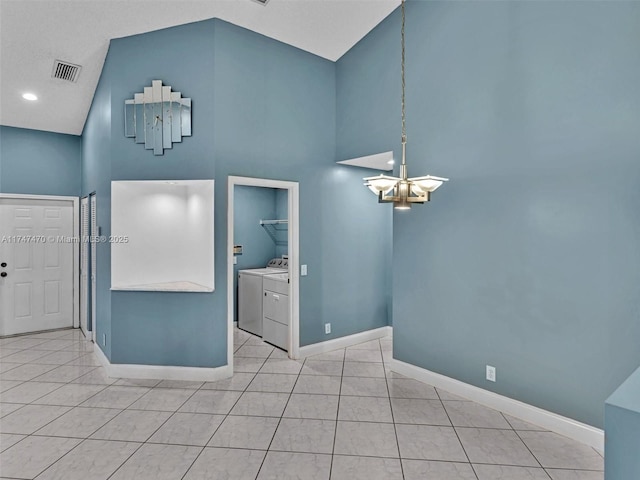 unfurnished room with washing machine and dryer, a high ceiling, an inviting chandelier, and light tile patterned floors