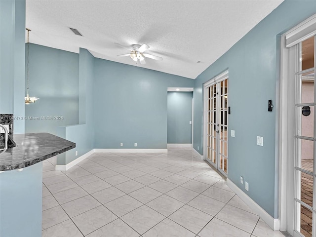 tiled empty room featuring a textured ceiling, french doors, vaulted ceiling, and ceiling fan with notable chandelier