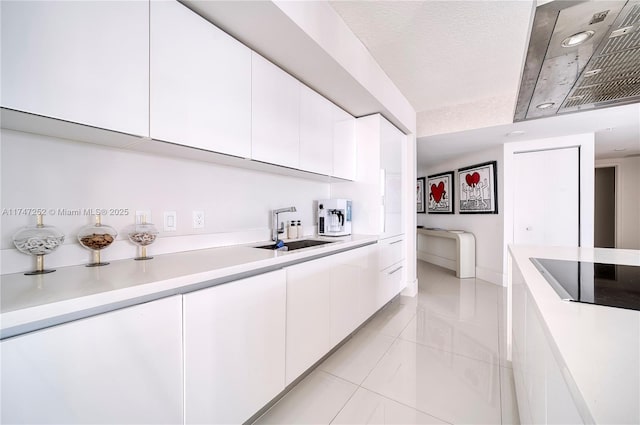 kitchen with black electric stovetop, a textured ceiling, white cabinets, light tile patterned flooring, and sink