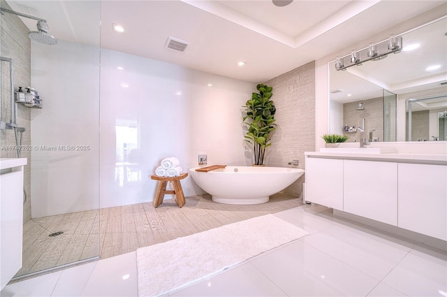 bathroom with independent shower and bath, tile walls, and vanity