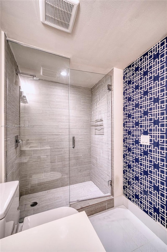 bathroom featuring a shower with door and toilet