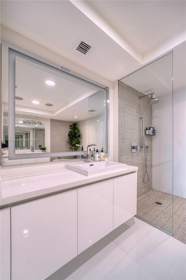 bathroom featuring tiled shower and vanity