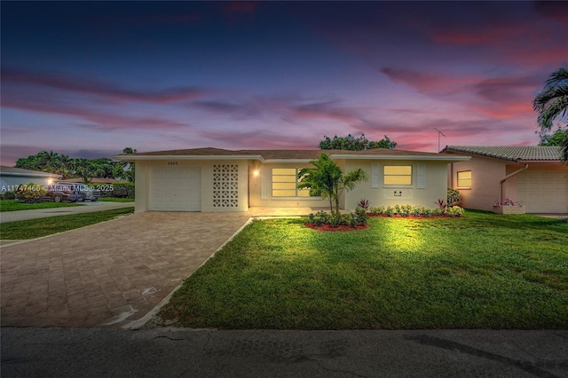 ranch-style home featuring a garage and a lawn