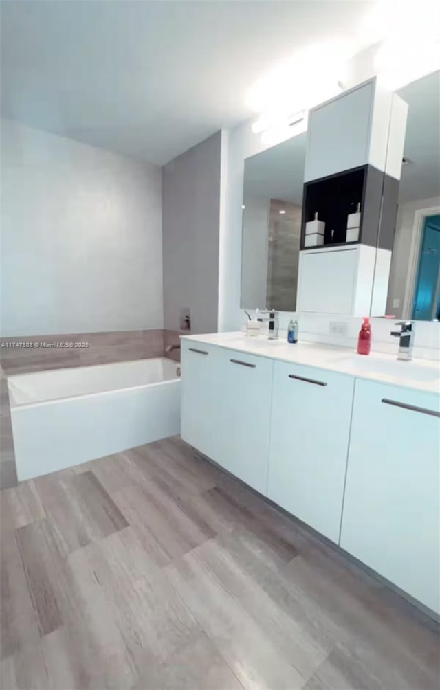 bathroom featuring hardwood / wood-style flooring, plus walk in shower, and vanity