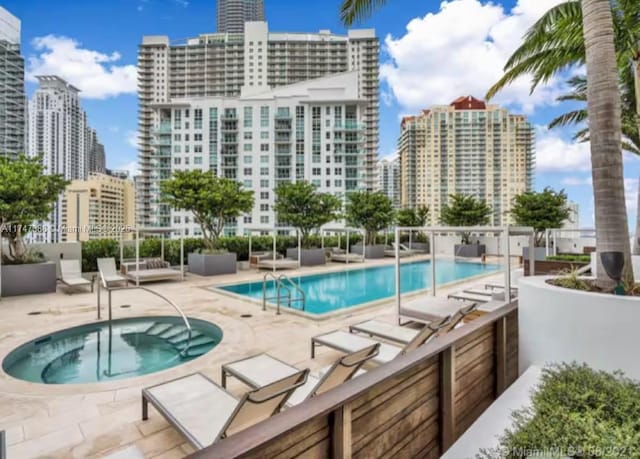 view of swimming pool with a patio area and a hot tub