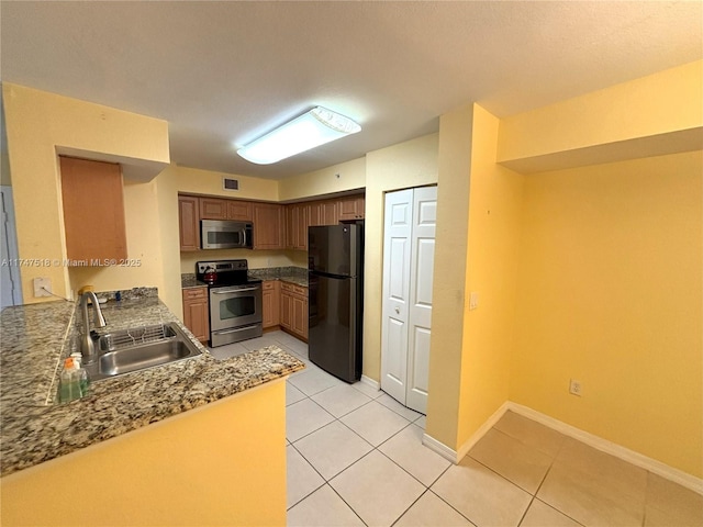 kitchen with light tile patterned flooring, appliances with stainless steel finishes, sink, and kitchen peninsula