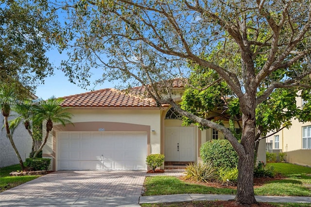 view of front facade with an attached garage, fence, a tile roof, decorative driveway, and stucco siding