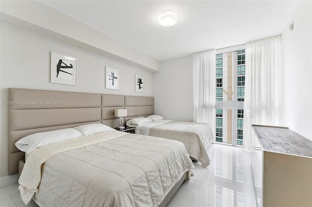 bedroom featuring multiple windows, a textured ceiling, and tile patterned floors