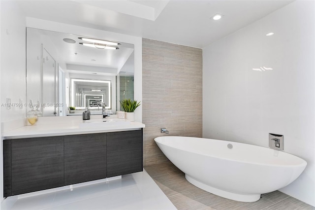 bathroom with a freestanding tub, tile walls, vanity, and tile patterned floors