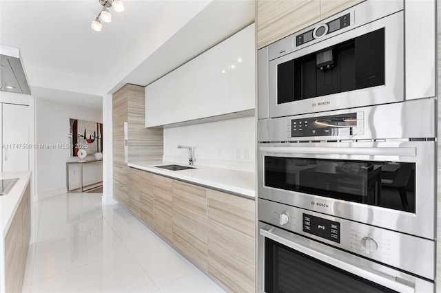 kitchen featuring light countertops, appliances with stainless steel finishes, white cabinets, a sink, and modern cabinets