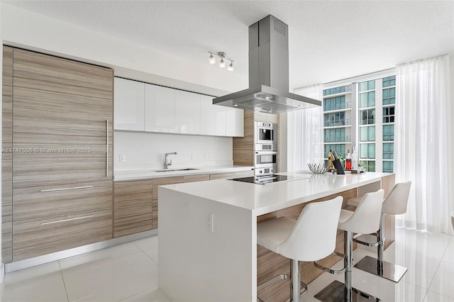 kitchen with island range hood, modern cabinets, a center island, black electric cooktop, and a sink