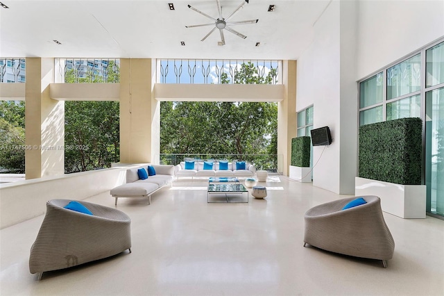 living area featuring expansive windows, a high ceiling, and finished concrete floors