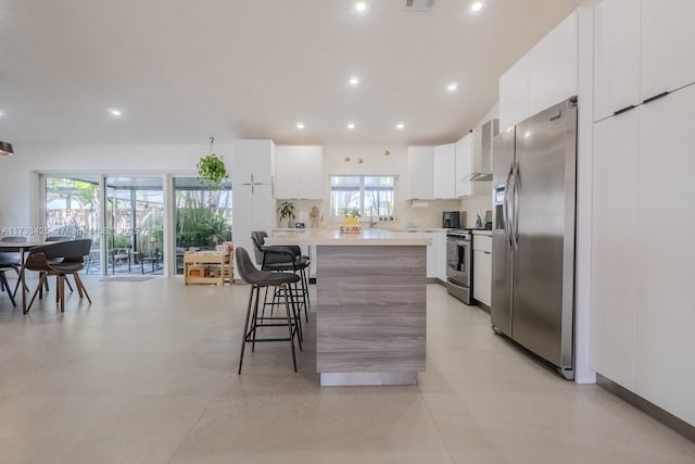 kitchen with a center island, stainless steel appliances, a breakfast bar, and white cabinets