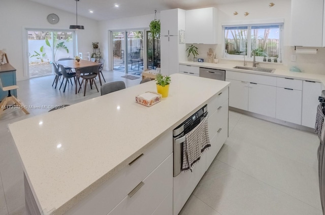 kitchen with a center island, hanging light fixtures, sink, tasteful backsplash, and white cabinets