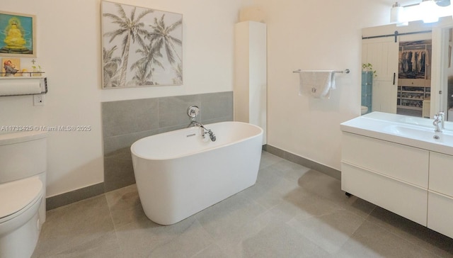 bathroom featuring tile walls, toilet, vanity, and a bath