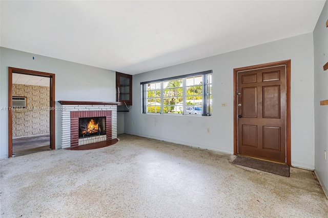 unfurnished living room with a fireplace and a wall mounted AC