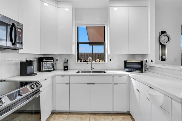 kitchen with white cabinets, stainless steel appliances, sink, and light tile patterned flooring