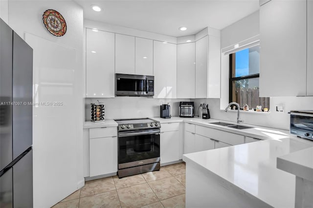 kitchen with light tile patterned flooring, white cabinetry, stainless steel appliances, and sink