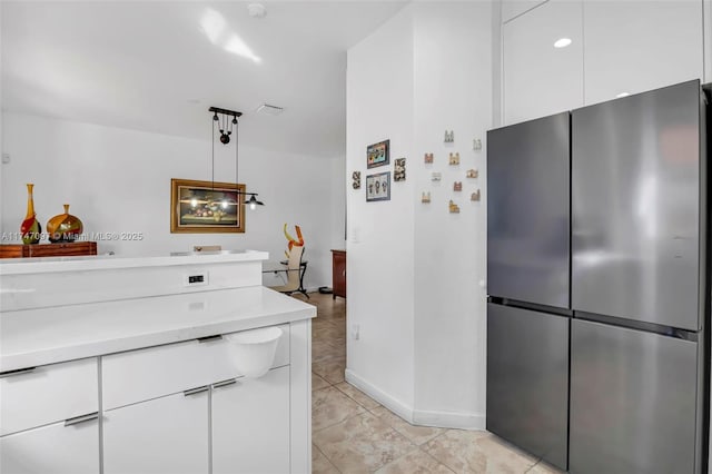 kitchen with stainless steel refrigerator, hanging light fixtures, light tile patterned flooring, and white cabinets